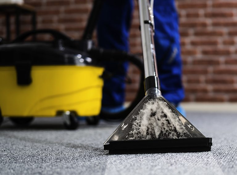 Janitor Cleaning Carpet With Vacuum Cleaner